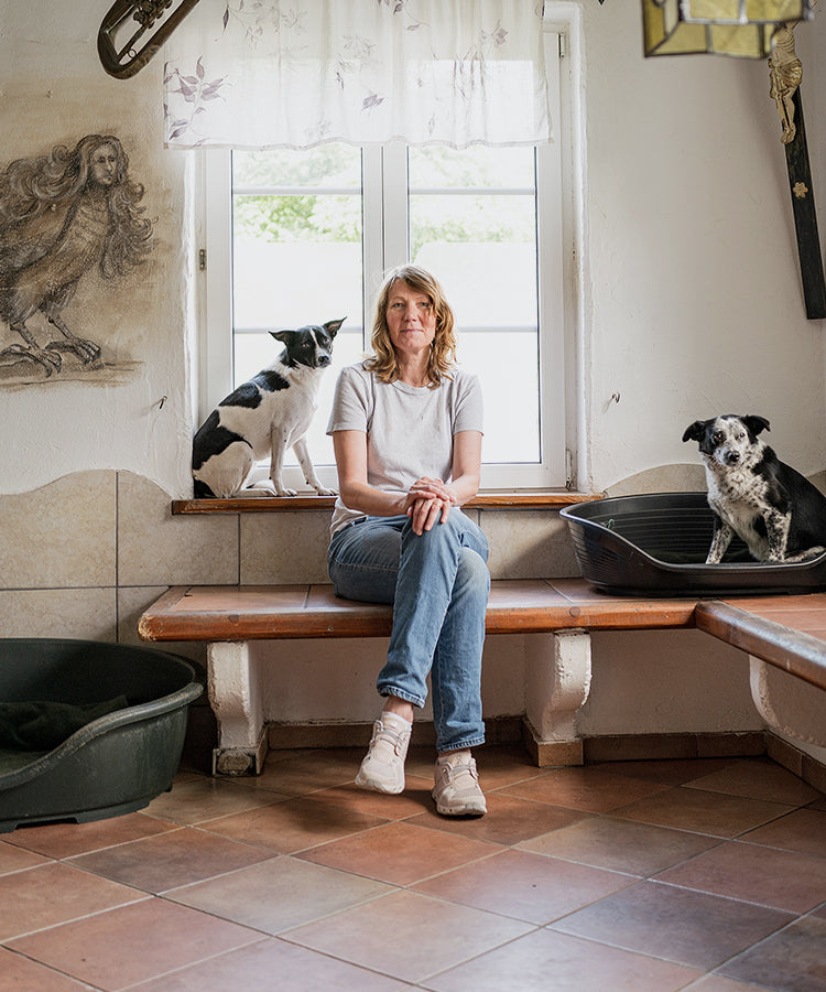 Cloud7 founder Petra Jungebluth sitting on a bench with two shelter dogs at ProAnimale