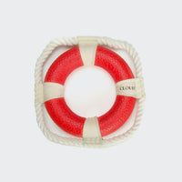CLOUD7_ Das Apportierspielzeug Rettungsring Floaty ist eine quadratische Rettungsboje mit einem roten kreisförmigen Mittelpunkt, weißem Seil an vier Punkten und CLOUDY-idealem schwimmfähigem Hundering als Apportierspielzeug Hund auf einem schlichten weißen Hintergrund.