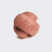 CLOUD7_ Das Beschäftigungsspielzeug Zeno Faded Rose ist ein rosafarbener Gummiball mit sich kreuzenden Bändern und CLOUD7-Prägung; dieses robuste Spielzeug dient auch als Leckerli-Spender, abgebildet auf einem schlichten hellen Hintergrund.