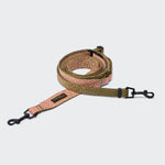 CLOUD7_ Eine aufgerollte L-3 Freihandleine AKTIV Knit in den Farben Khaki/Pfirsich mit gemustertem Design und schwarzen Metallklammern an beiden Enden, gefertigt aus Aktiv-Knit-Material und auf hellgrauem Hintergrund abgebildet.