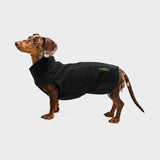 Ein brauner Dackel steht vor einem schlichten Hintergrund und trägt den „Body Warmer Dackel AKTIV Black“ – eine stilvolle Fleecejacke mit einem kleinen Logo an der Seite, die gleichzeitig als funktionelle Wärmeschicht dient und Ihrem Haustier Wärme und Komfort bietet.