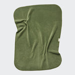 CLOUD7_ Die Hundedecke „Fleece Moss Green“ ist eine rechteckige, olivgrüne Mikrofaserdecke mit leicht unregelmäßigen Kanten und einem kleinen weißen Etikett. Sie liegt flach auf und weist sichtbare Falten auf; dank ihrer weichen, fleeceartigen Struktur eignet sie sich ideal als waschbare Hundedecke oder als praktische Hundedecke für das Auto.