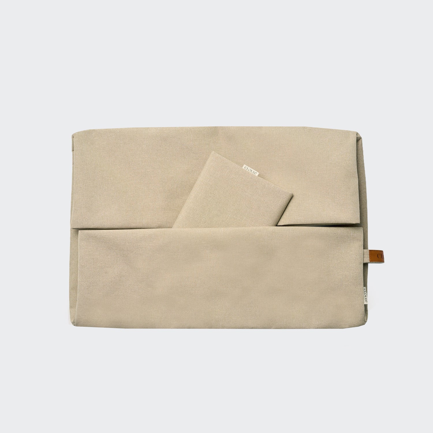 Ein beiger Stoffbeutel mit einer Vordertasche und einem kleinen beigen Notizbuch, das teilweise darin steckt, vor einem schlichten hellgrauen Hintergrund – perfekt zum Ordnen Ihrer wichtigsten Dinge, ganz im praktischen Stil des „Outdoor Wechselbezug Sleepy Deluxe Sand“.
