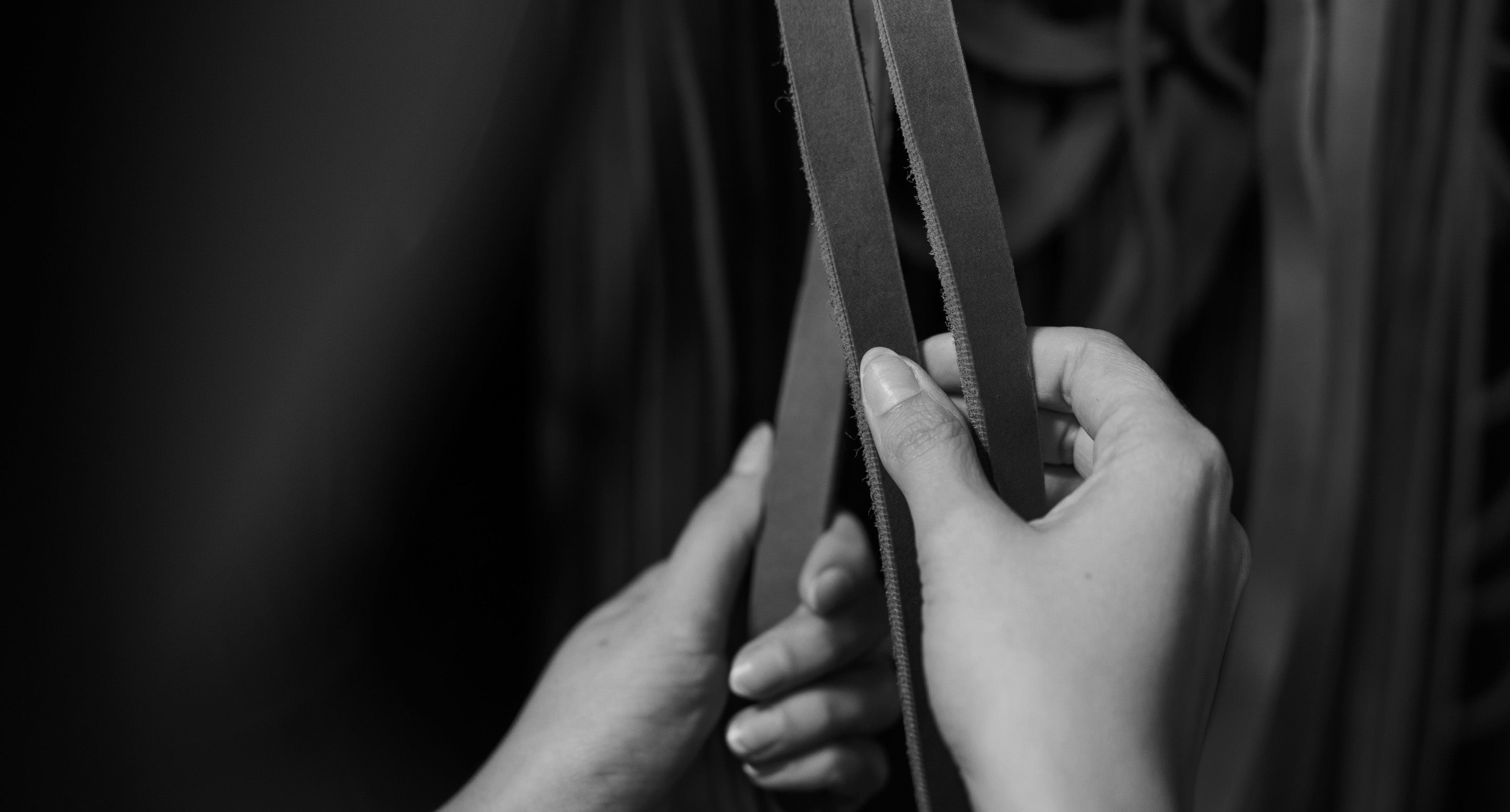 Hands holding strands of leather 