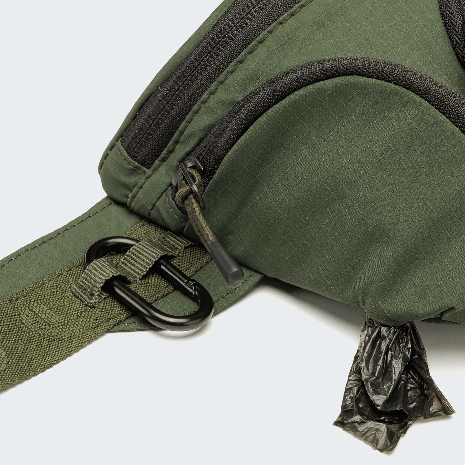 Close-up of the Gürteltasche AKTIV Olive with a black zipper, strap featuring a metal clip, and black waste bags partly pulled out from a side pocket—perfect for Hundetraining or as a praktische Gürteltasche Hund.
