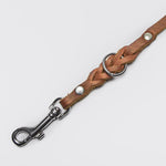 Silver carabiner of a light brown leather dog leash with braided elements