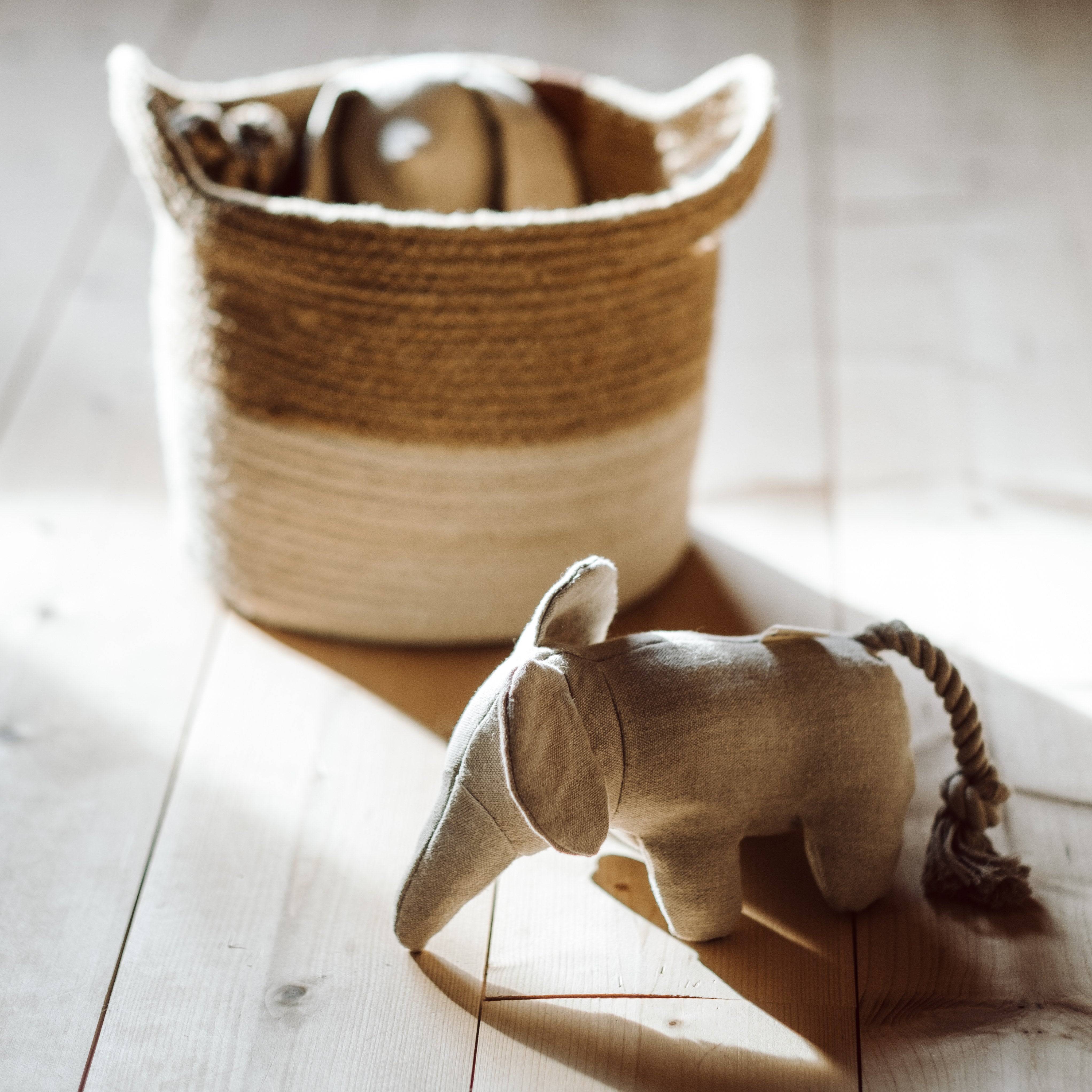 Beige hemp dog toy in elephant shape in front of storage basket